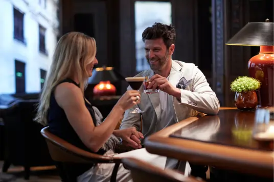 Man und Frau sitzen in der Bar mit einem Cocktail in der Hand