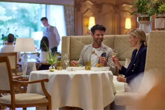 Ein Mann und eine Frau, die im Restaurant sitzen und mit zwei Weingläsern anstoßen.