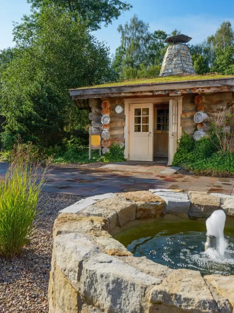 Eine Blockhüte steht in einer ruhigen Steingarten-Landschaft mit einem Springbrunnen